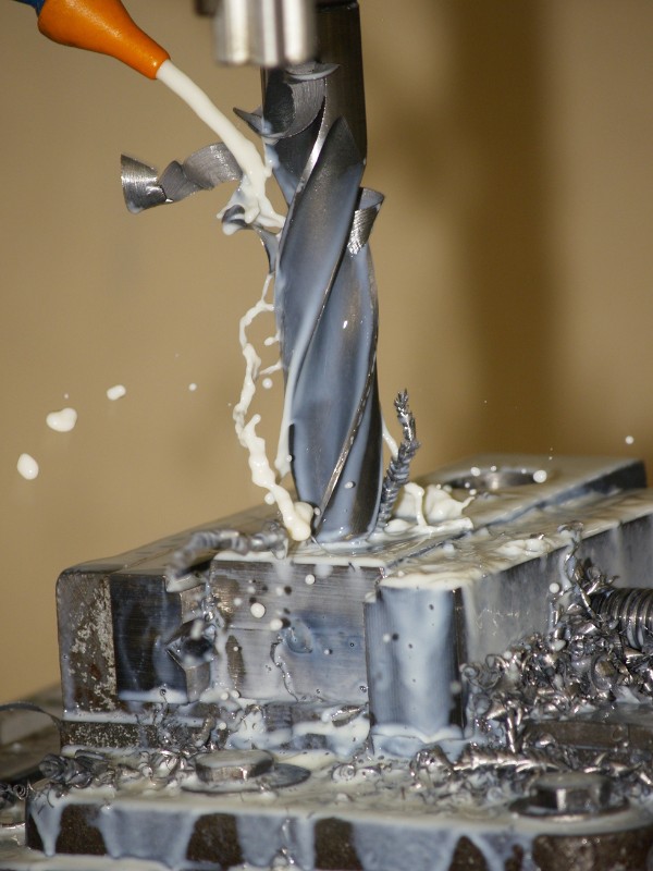 Metallbearbeitung Eine Fräsmaschine bearbeitet ein Werkstück in einer Metallbearbeitungsmaschine, während sie mit Kühlschmierstoffen gekühlt wird.